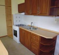 A kitchen in a 2-room apartment with cabinets and white tiles.