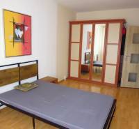 Bedroom with a bed, wooden decor flooring, and a wardrobe in a 2-room apartment.