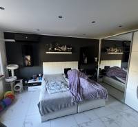 A bedroom in a two-room apartment with white furniture, decorations, and cat accessories.