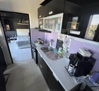 A kitchen with purple tiles and modern equipment in a 2-room apartment.