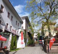 A narrow courtyard with three-story buildings and café chairs on Hlavná Street in Prešov.