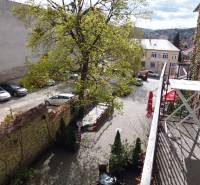 View from the balcony of a 3-room apartment on Hlavná Street in Prešov with a parking lot and greenery.
