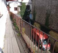 Narrow balcony with wooden decor above the courtyard and a red van, Main Street, Prešov.
