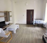 Living room in a three-room apartment with light furniture and a wooden decor floor.