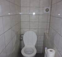 A toilet in a 3-room apartment with tiles and a ventilation opening.
