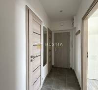 A hallway with light doors in a 2-room apartment, gray tiles on the floor.