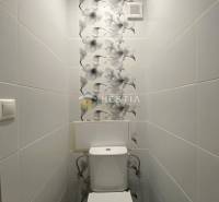 A toilet with patterned tiles in a 2-room apartment.