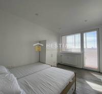 Bedroom with a bed, wardrobe, and large window in a two-room apartment.