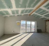 An unfinished room in a family house with windows and a view of the garden.
