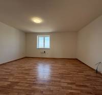 A spacious room with a window and a wooden decor floor in a family house.