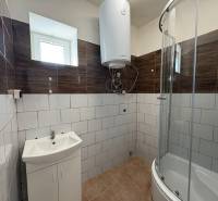 A bathroom in a family house with a modern shower and light tiles.
