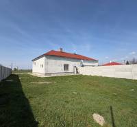 A family house in Zemianska Olča with a white facade and a red roof on a grassy plot.