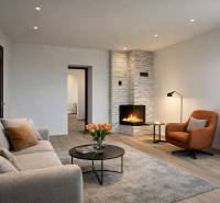 Living room with a fireplace, comfortable seating, and a wooden decor floor in a family house.