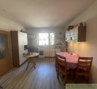 A kitchen in a family house with a wooden floor decor, simple furniture, and a dining table.