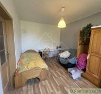 A room in a family house with a bed, a table, and a floor with a wooden decor.