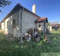 A family house in Jatov with wooden cladding and a garden full of flowers and logs.