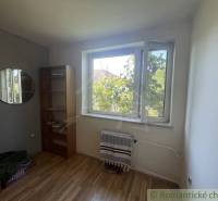 A room in a family house with a wooden decor floor, a window, and a shelf.