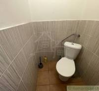 A toilet in a family house with ceramic flooring and tiles.