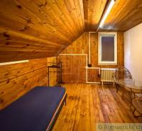 Interior of a cabin with a wooden decor floor, bed, and chairs for comfort.