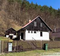 A cottage in Moštenica surrounded by forests, a fence and a trash can in the yard.