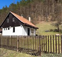 A cottage in Moštenica surrounded by a fence and forest, nestled in nature.