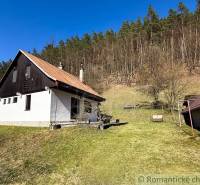 A cottage in Moštenica surrounded by a grassy plot and forest in the background.