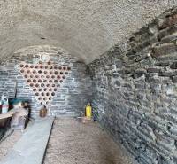 Stone cellar in the vineyard with storage space for wine and a shelf for containers.