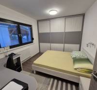 Bedroom in a family house with a bed, desk, and wardrobe.