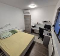 A bedroom in a family house with a desk and a wooden decor floor.