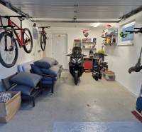 A family house garage with bicycles, a motorcycle, and shelves with tools and accessories.