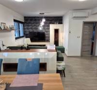 Living room with a television, wooden decor flooring, sofa, and decorative wall.