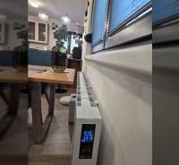 The interior of a family house with a decorative table, heating equipment, and a floor with a wooden decor.
