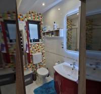 A bathroom in a family house with colorful tiles and light walls.