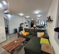 Living room in a family house with a sofa, wooden table, and ceiling lights.