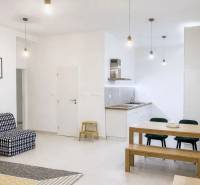 Interior of a 2-room apartment with a simple white kitchen and wooden furniture.