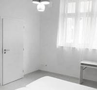 White room with a double bed, table, and pendant lighting in a 2-room apartment.