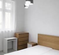 A bedroom with wooden furniture and pendant lighting in a two-room apartment.