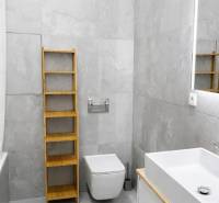 Bathroom in a 2-room apartment with gray tiles, a sink, and a shelf.