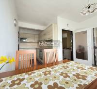 A bright kitchen in a family house with wooden furniture and a decorative tablecloth.