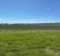 Agricultural and forest land in Dežerice with expansive meadows and a clear sky.
