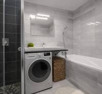 A bathroom in a 3-room apartment with a washing machine, shower, and bathtub, light tiles.