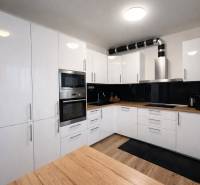 A kitchen in a 3-room apartment with white cabinets and a wood-patterned floor.
