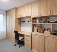 A workspace in a 3-room apartment with a wooden decor and plenty of shelves for books.