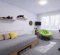 Children's room in a 3-room apartment with a bed, toys, and a green armchair.