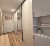 A hallway in a 3-room apartment with a wooden-patterned floor and built-in wardrobes.
