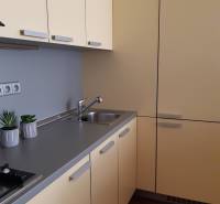 A kitchen in a 3-room apartment with cream cabinets and a wooden decor floor.