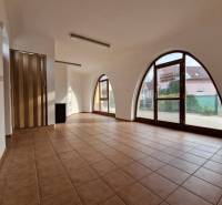 Interior of commercial spaces with large arched windows, tiled floor, and wooden doors.