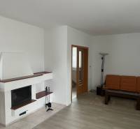 Living room with a fireplace, orange sofa, wood-patterned floor, and glass table.