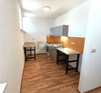 A kitchen in a 2-room apartment with a wooden decor floor and white walls.