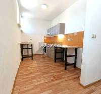 A kitchen in a 2-room apartment with a wooden decor floor and orange tiles.